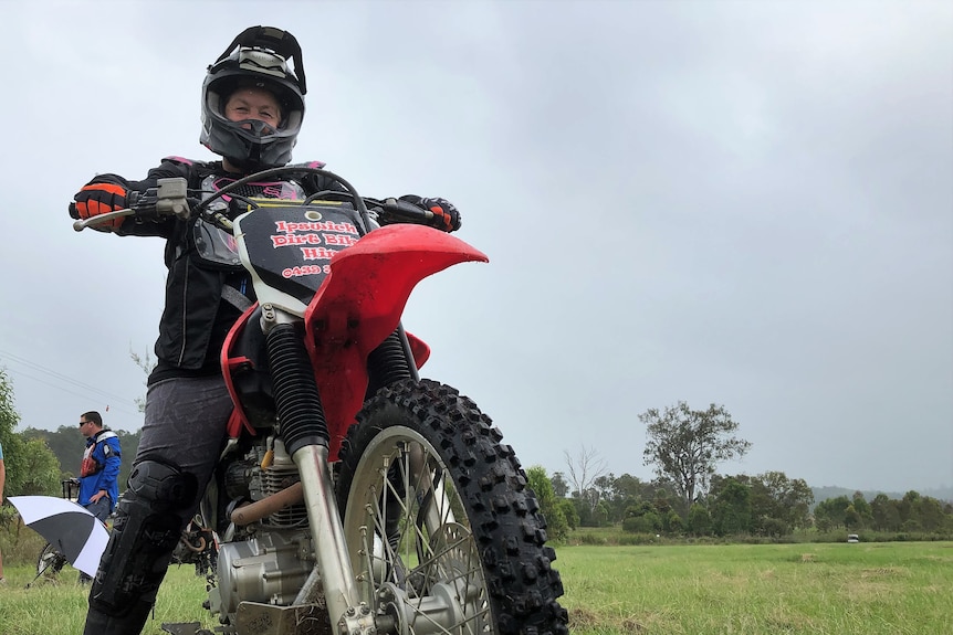 Helen pictured on red bike wearing a black helmet with both hands on the steering, 