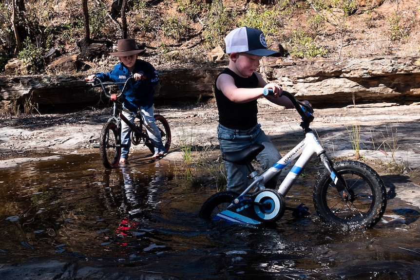 young boys playing with their bikes in the water