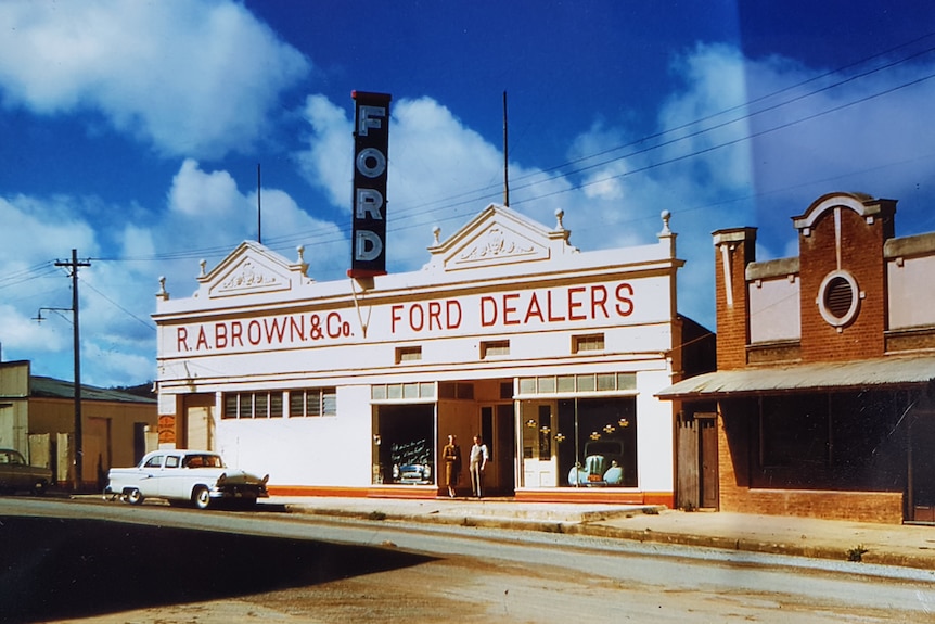 A man and woman standing in a doorway of a Ford car dealership building.