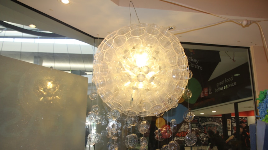 A chandelier made out of plastic cups and the bottom of plastic bottles hangs