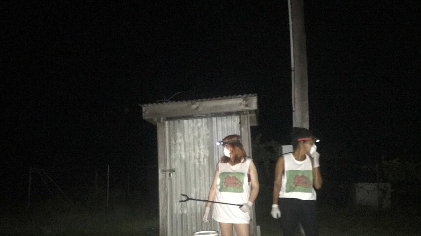 A photo of two girls catching cane toads in the Torres Strait Islands.