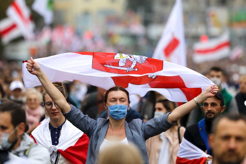 A demonstrator wearing a face mask to protect against coronavirus waves an old Belarusian national flag