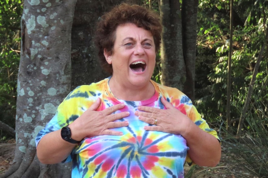 A woman in a tie-dye T-shirt instructing a yoga class