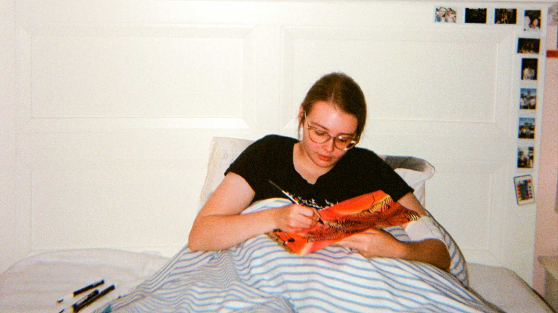 A young woman makes a painting while sitting in bed