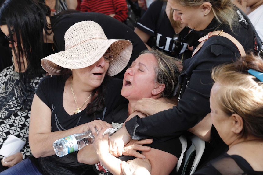 A woman wails as others try to carry her.
