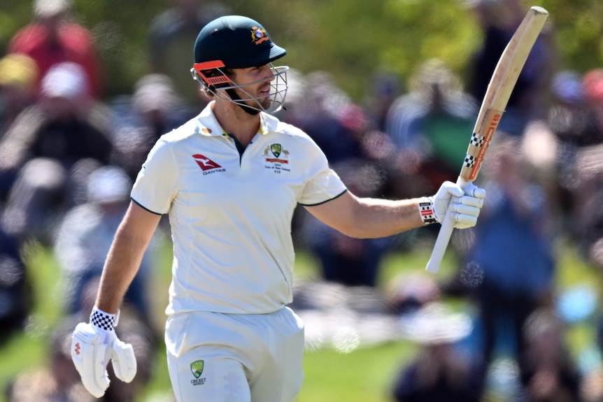 Mitch Marsh holds up his bat to the crowd after making a half-century