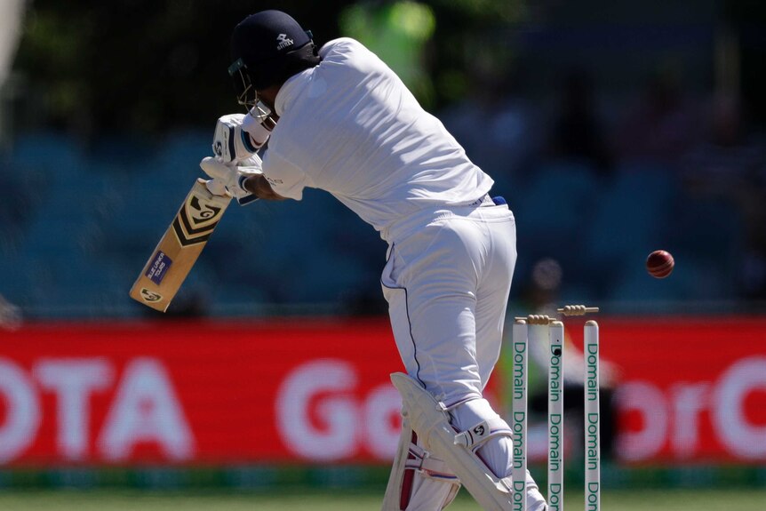 One bail is slightly dislodged from the stumps as the batsman plays a shot and the ball sails through.