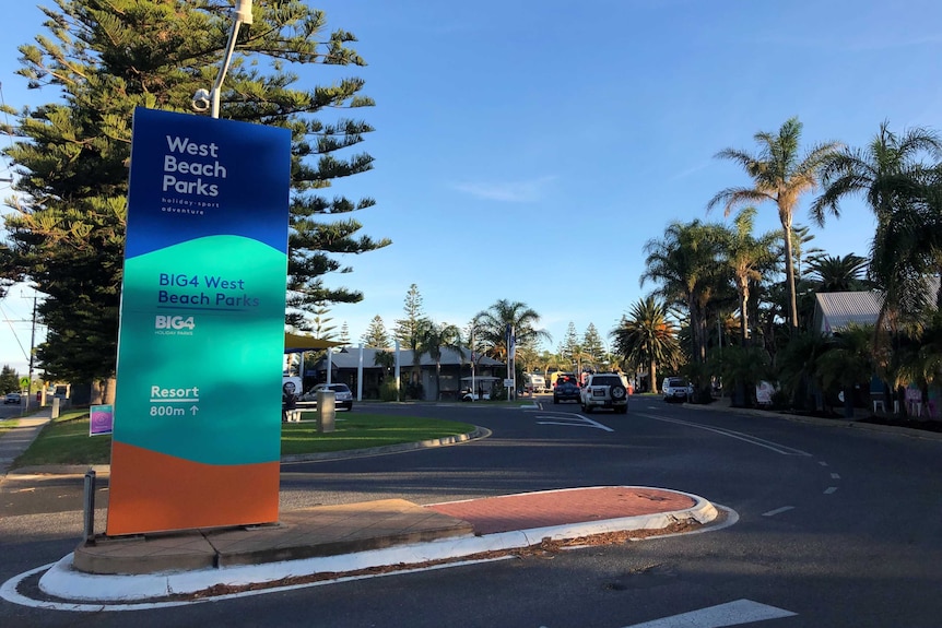 A blue and green sign in front of a caravan park