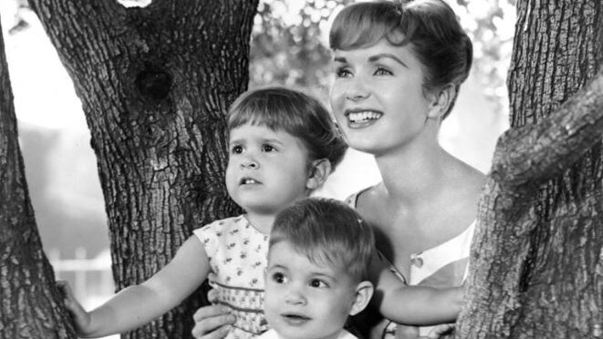 Woman with two children poses in tree