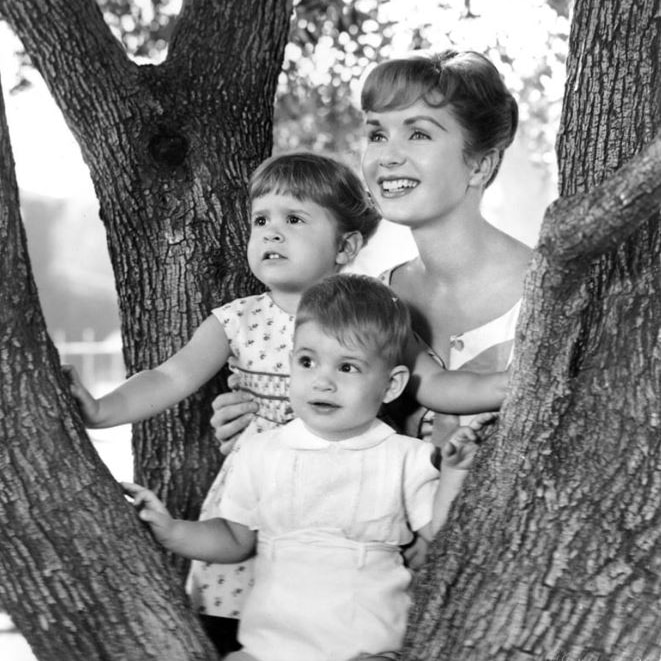 Woman with two children poses in tree