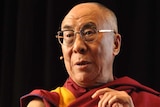 The 14th Dalai Lama sits down and gestures during a speech in Brisbane on July 15, 2011.