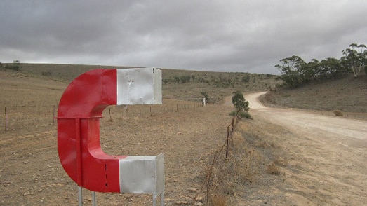 A large magnet symbol that is red and white on the edge of Magnetic Hill., a tourist attraction at Orroroo SA