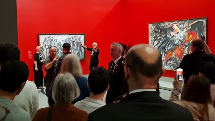 two people glued to a painting while others watch.