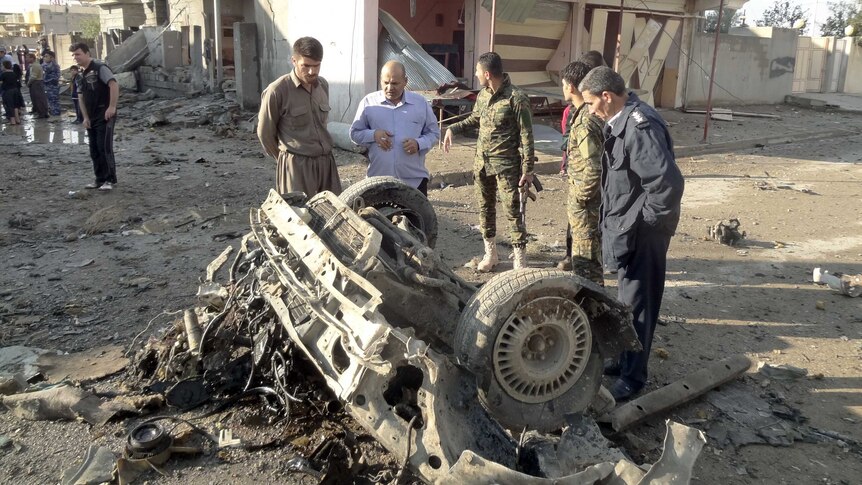 Iraqis look at the remains of a one of two car bombs in the northern Iraqi city of Kirkuk.