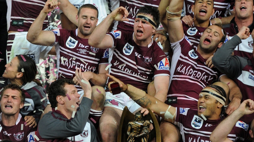 Victory is sweet ... Manly players celebrate with the premiership trophy after escaping the Warriors.
