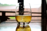 A glass of whisky sits on a table in front of a window