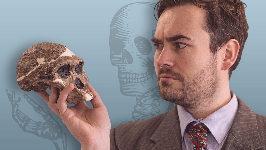 BTN reporter Matthew Holbrook holding up a human skull and looking at it inquisitively.