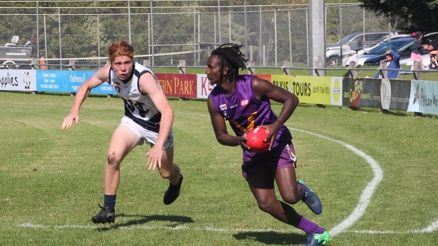 Two men play AFL football in Port Fairy