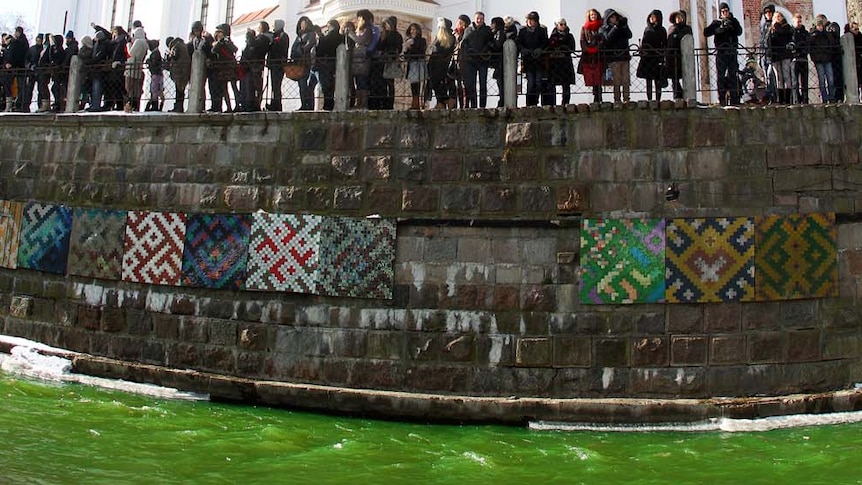 Locals watch the river Vilnele turn green