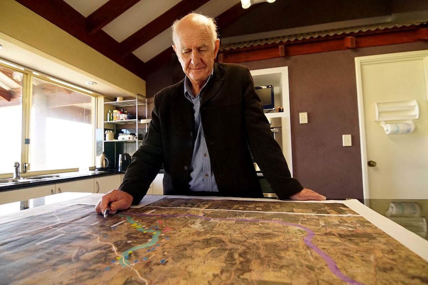 Kevin Renton stands over a map of proposed new truck routes near Bindoon.