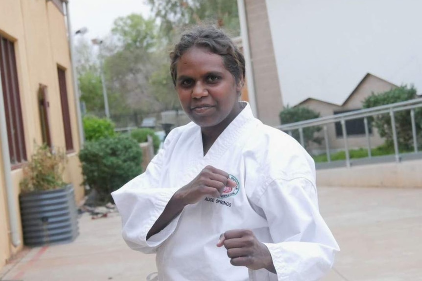 Indigenous teenager Chrissie Davis looks at the camera in karate gear, with fists raised.