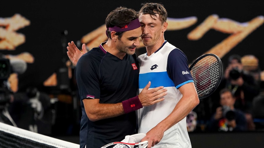 Two male tennis players embrace at the net at the ned of their match at the Australian Open.