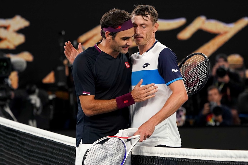 Two male tennis players embrace at the net at the ned of their match at the Australian Open.