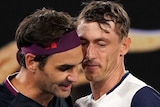 Two male tennis players embrace at the net at the ned of their match at the Australian Open.