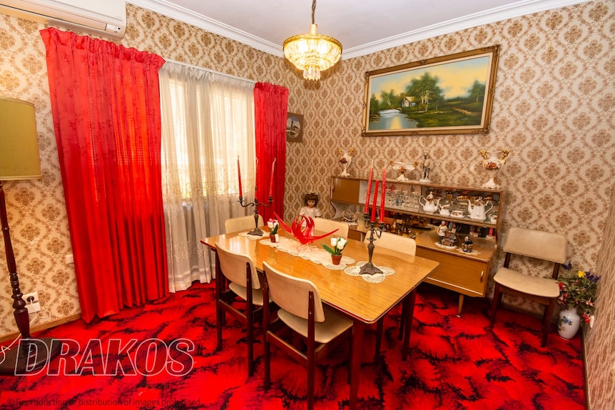 Formal dining room featuring wooden table with five chairs, and window with red curtains