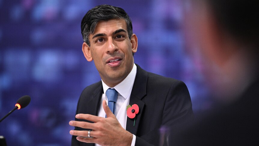 Rishi Sunak, wearing a suit, gestures with his hand.