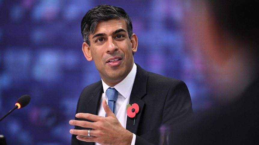 Rishi Sunak wearing suit gestures with hand 