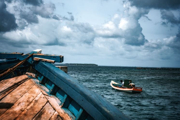 A wooden boat sits next to another boat in the South China Sea.