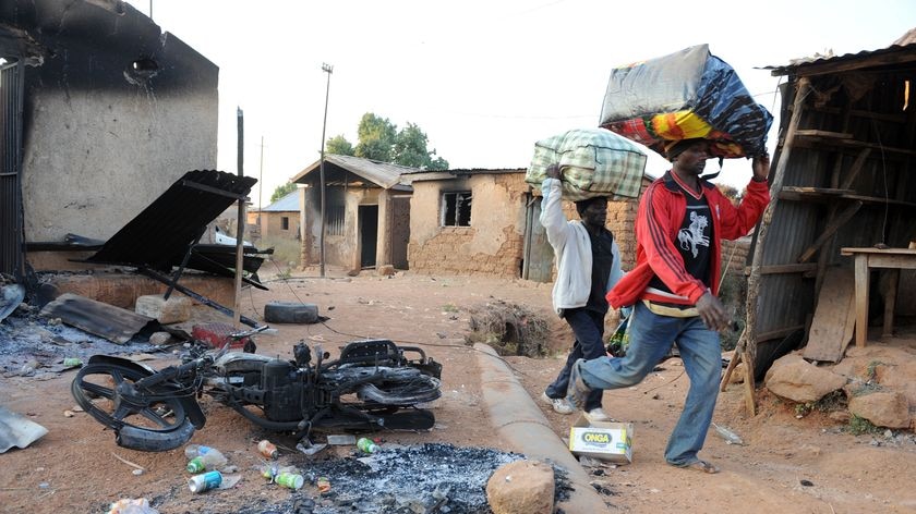 Residents walk past a burnt building in Nigeria