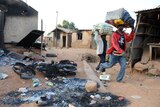 Residents walk past a burnt building in Nigeria