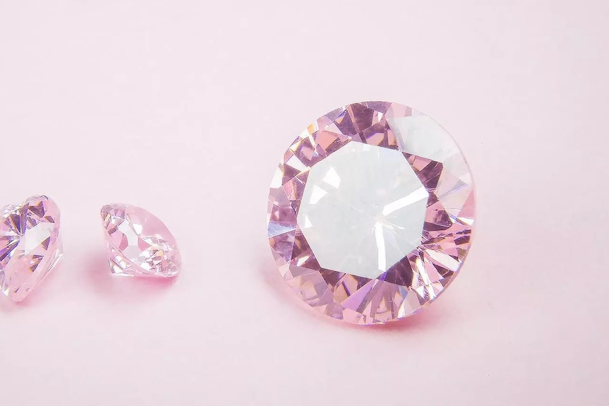 Three pink diamonds sitting against pink background