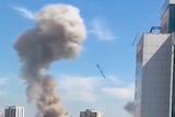 A thick plume of smoke rises above a building after a missile falls on it. 