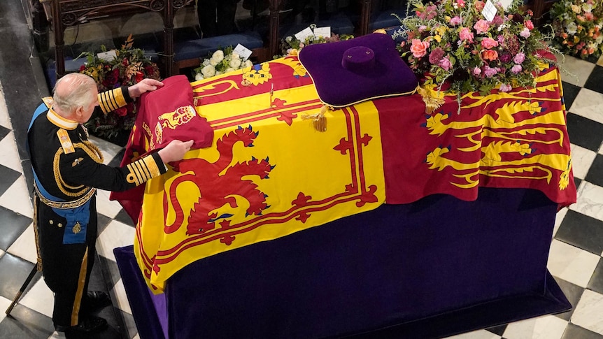 Charles places fabric on top of queen's coffin