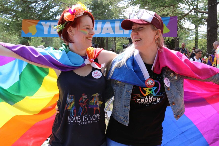Two women hold a rainbow flag in Canberra's Haig Park.