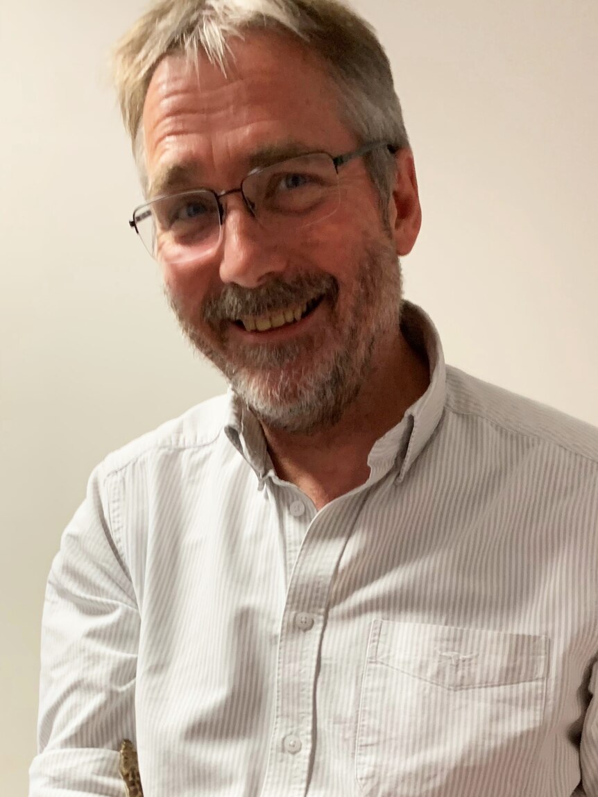 A man with glasses on smiles at the camera.