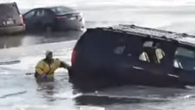 A car is half submerged in icy water.
