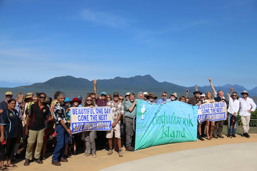 A group of opponents to the proposed lease on the island hold banners and signs