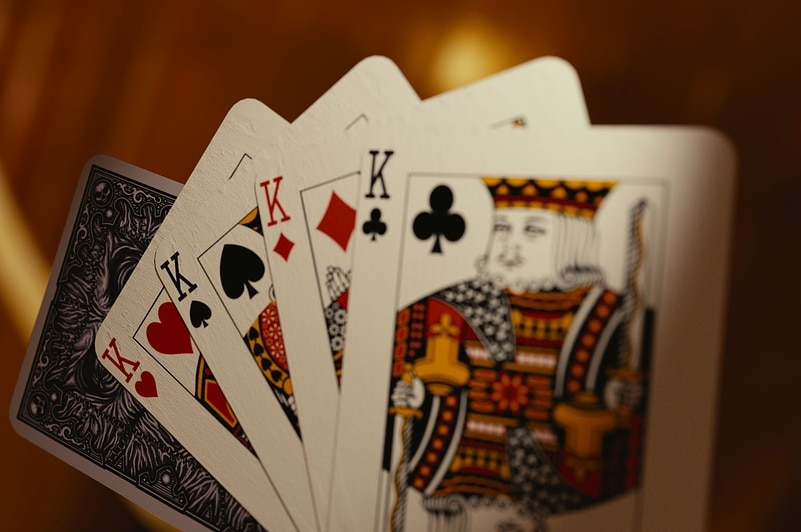 Playing cards fanned out, featuring a 'four-of-a-kind' King of hearts, spades, diamonds and clubs.