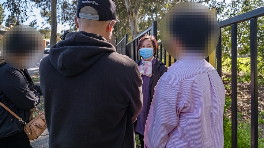 A group of four stand outside a fence.