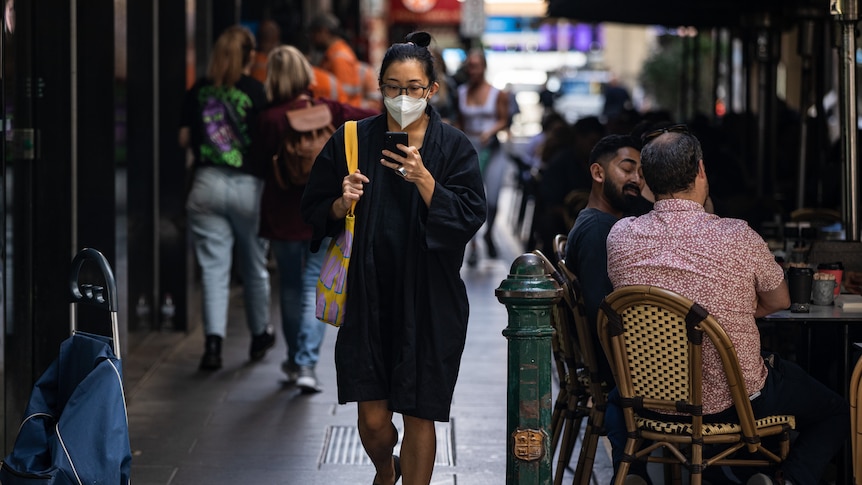 A woman is seen wearing a face mask as she walks