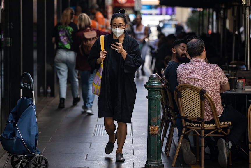 A woman is seen wearing a face mask as she walks