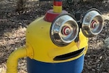A minion with dog bowls for eyes rests next to a more conventional mailbox. Both have the word "Warren" on them