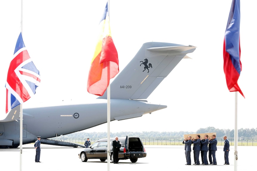 Men carry a coffin containing human remains collected at the MH17 crash site in Ukraine.