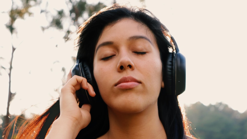 Woman with eyes closed, wearing headphones