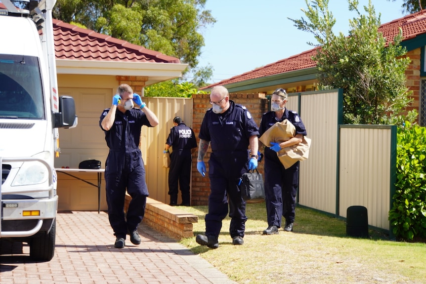 Four police forensic officers outside a home, one of them carrying a bag