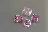Four pink coloured diamonds and a pair of tweezers.